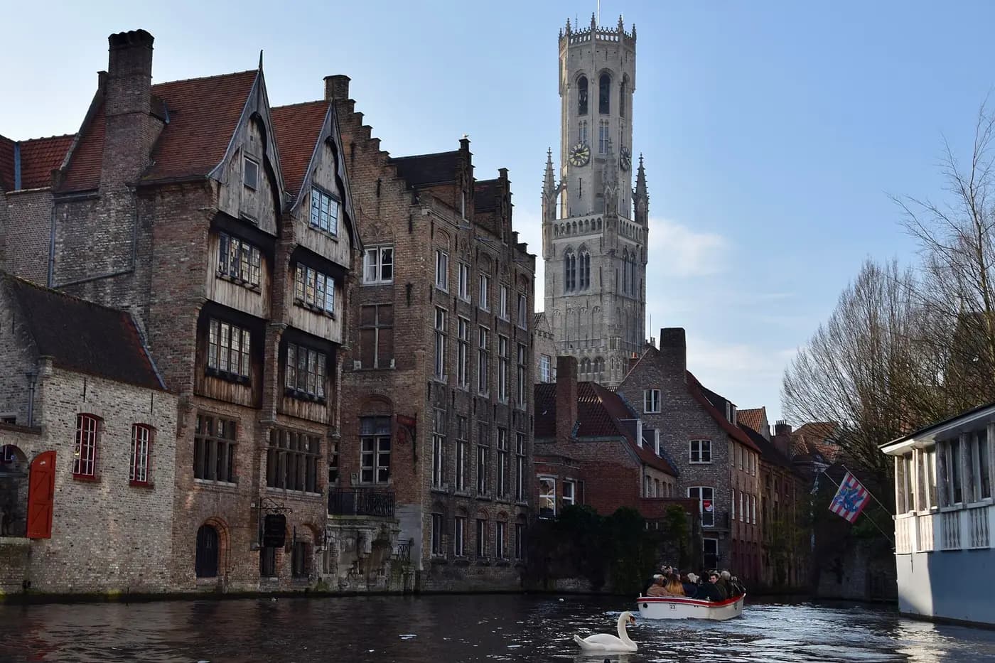 Old brick houses on the Rozenhoedkaai canal in Bruges, with the Belfry tower behind