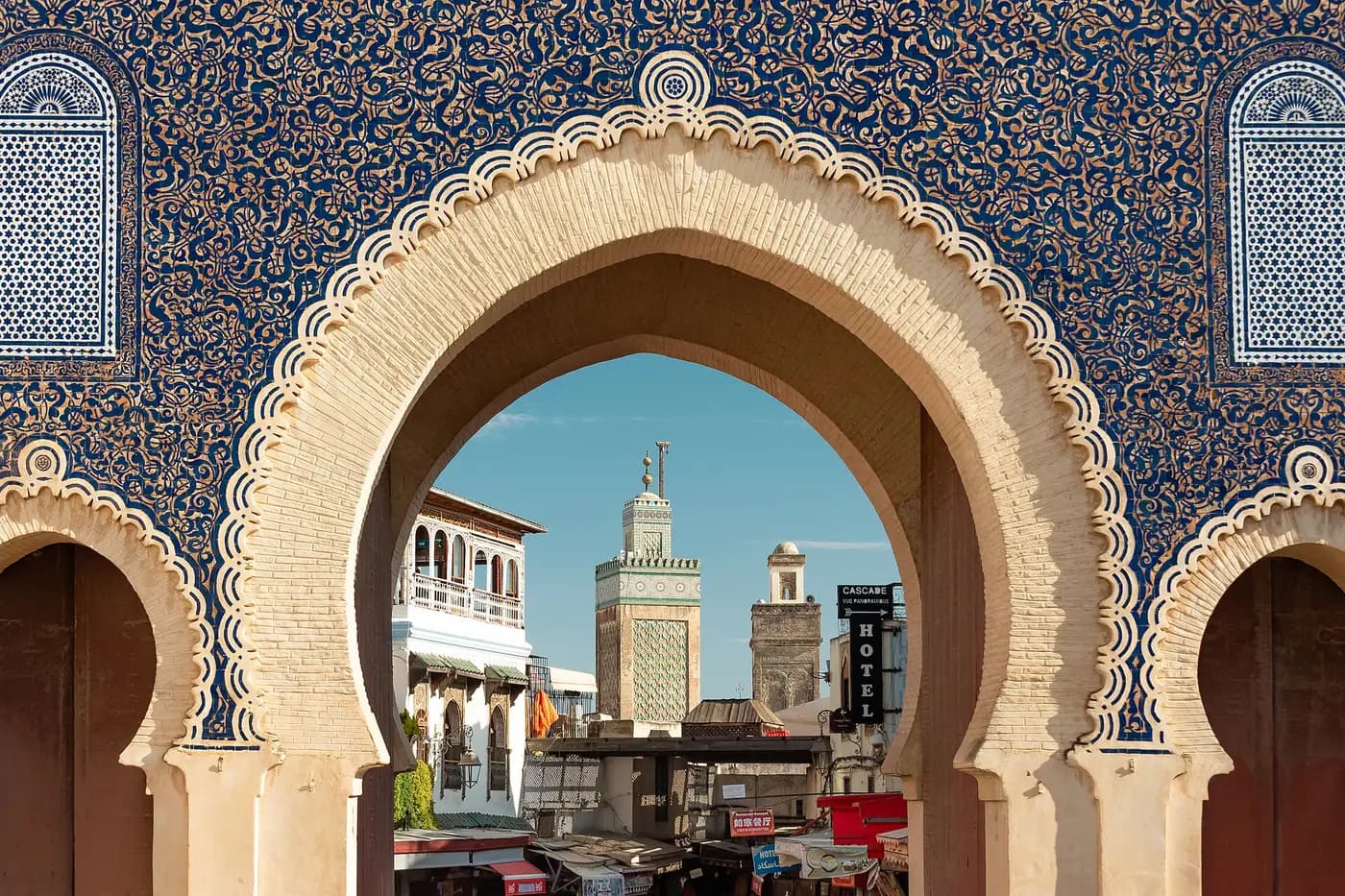 Minarets of the Fez medina framed by the blue-tiled horseshoe arches of the Bab Bou Jeloud gate