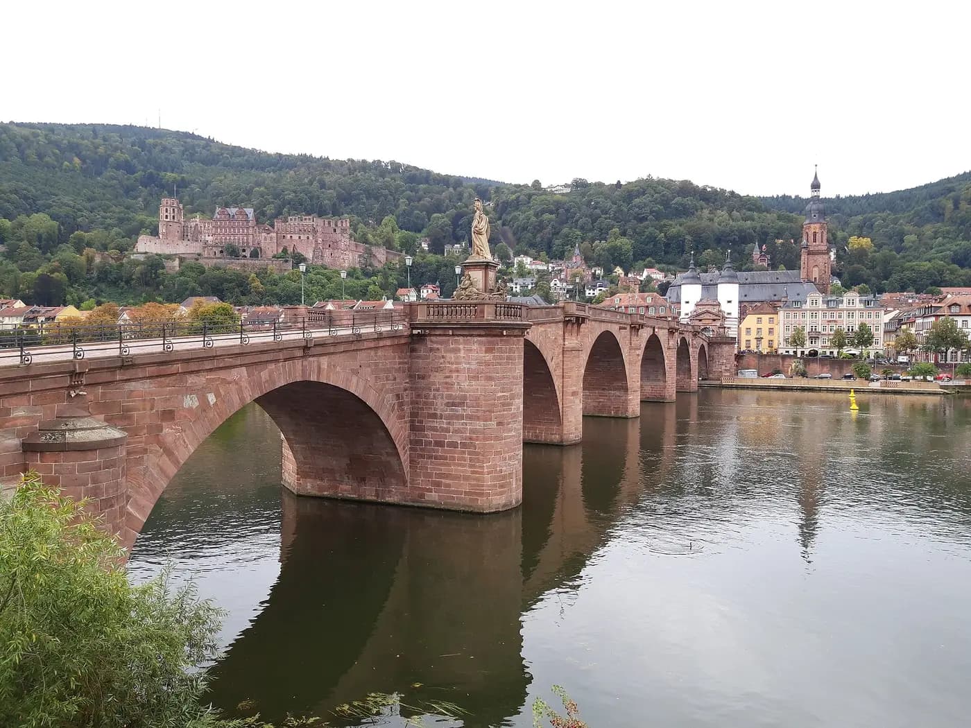 Heidelberg's red sandstone Old Bridge over the Neckar, with the old town and castle on the wooded hillside