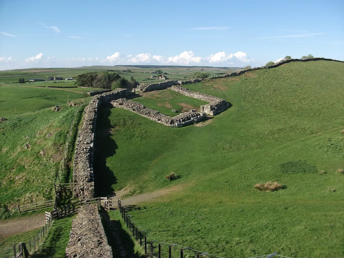 Hadrian's Wall climbing over Northumberland hills past the stone footings of Cawfields milecastle