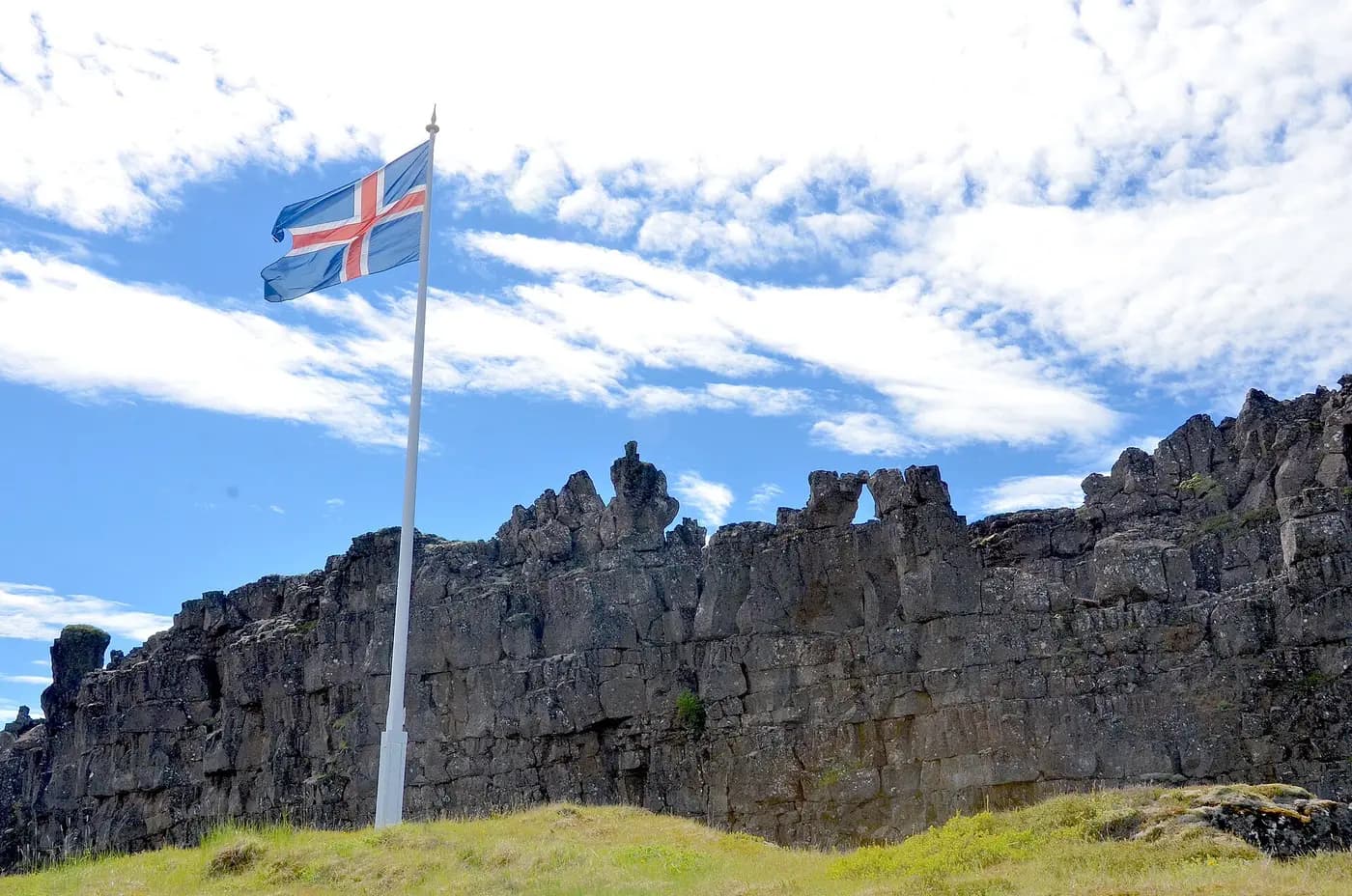 The Icelandic flag flies at Lögberg, the Law Rock, beneath the lava cliffs of Almannagjá
