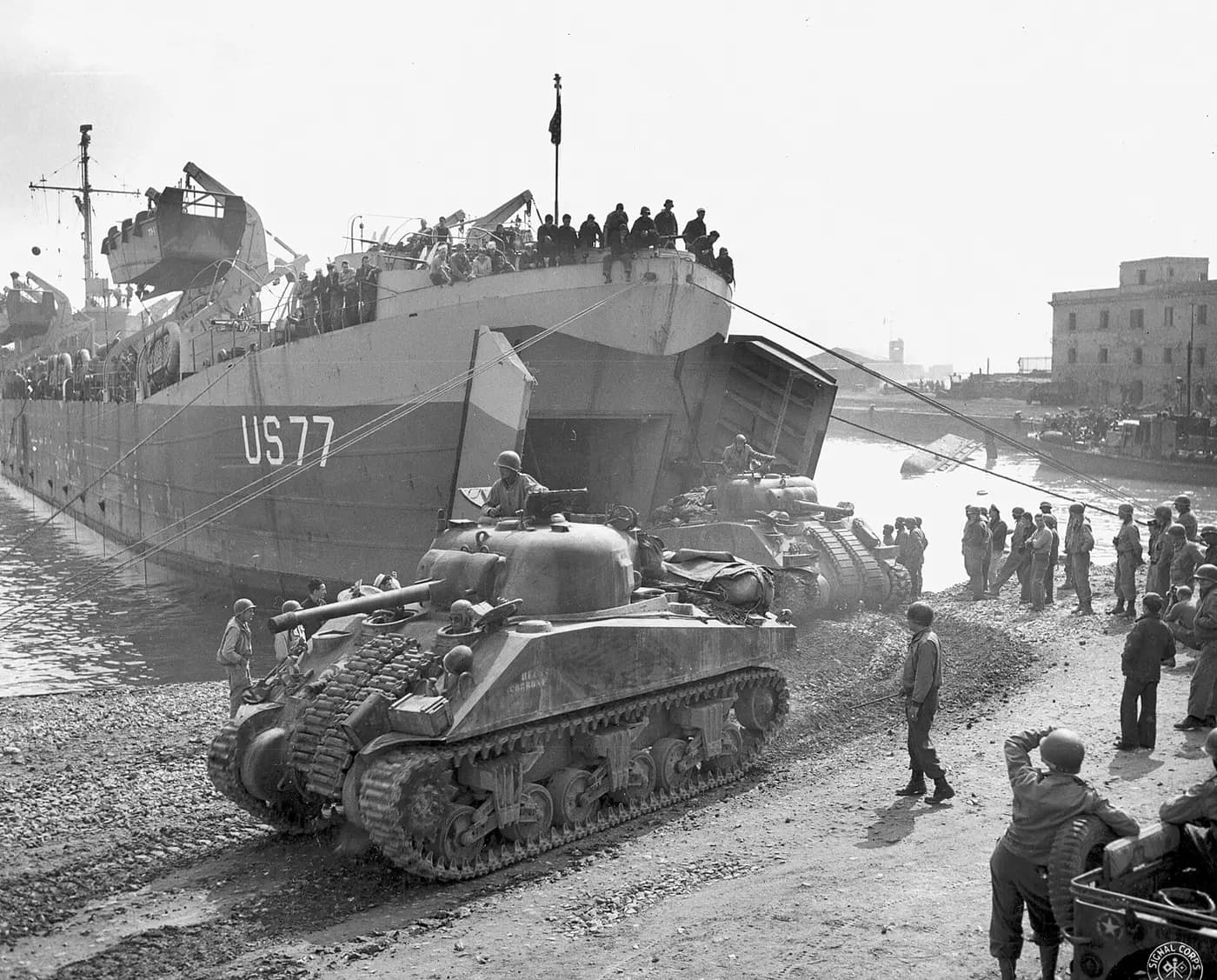 Sherman tanks roll off a US landing ship onto the quay at Anzio in 1944