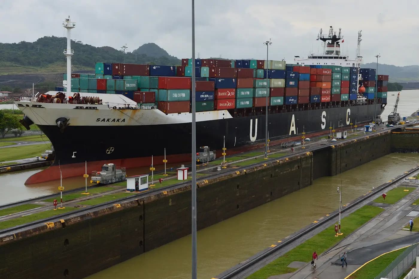 A container ship in the Miraflores Locks, guided by electric locomotives running along the lock walls