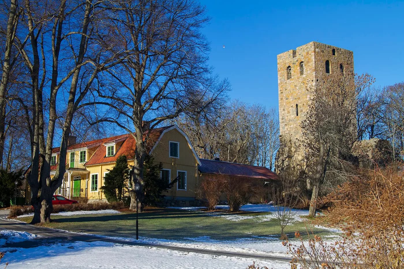 The ruined stone tower of St Per's church in Sigtuna beside the old vicarage, in winter sunshine