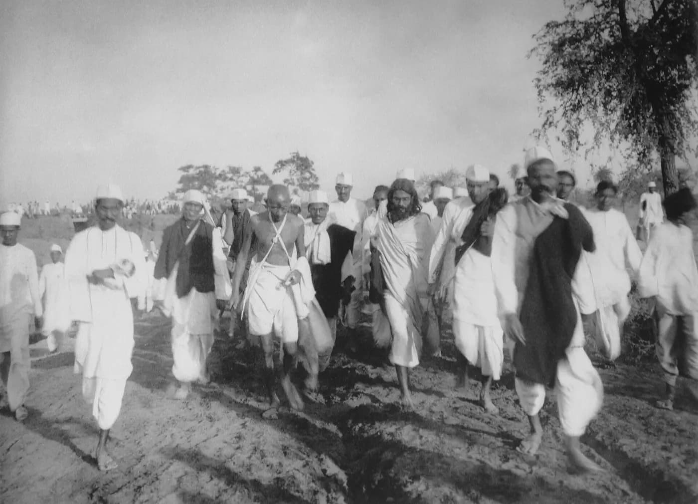 Gandhi walks with marchers along a dusty road during the Salt March, 1930