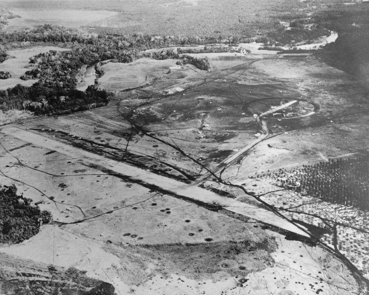 Aerial view of the cratered Henderson Field airstrip on Guadalcanal in August 1942, with the Lunga River beyond