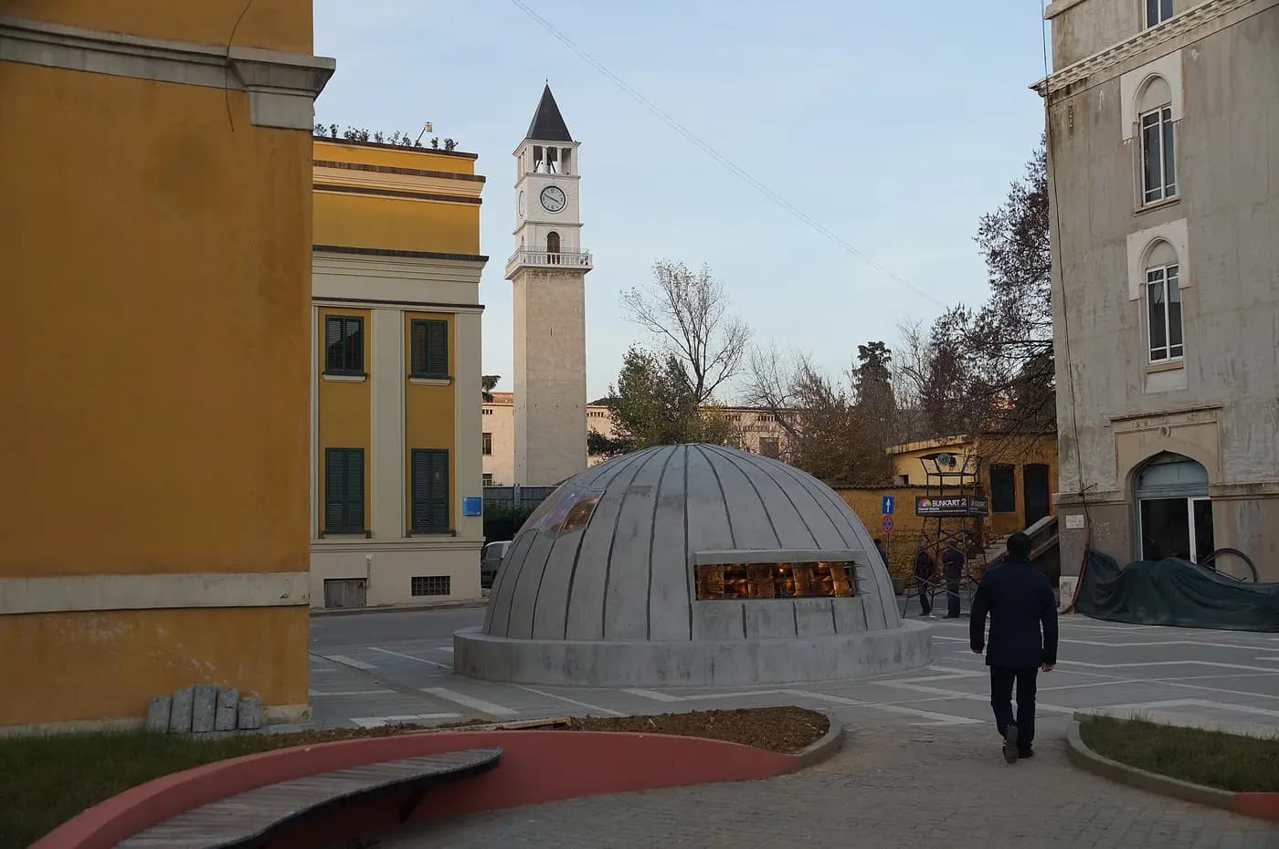 A concrete bunker dome marks the entrance to Bunk'Art 2 in central Tirana, with the Clock Tower behind