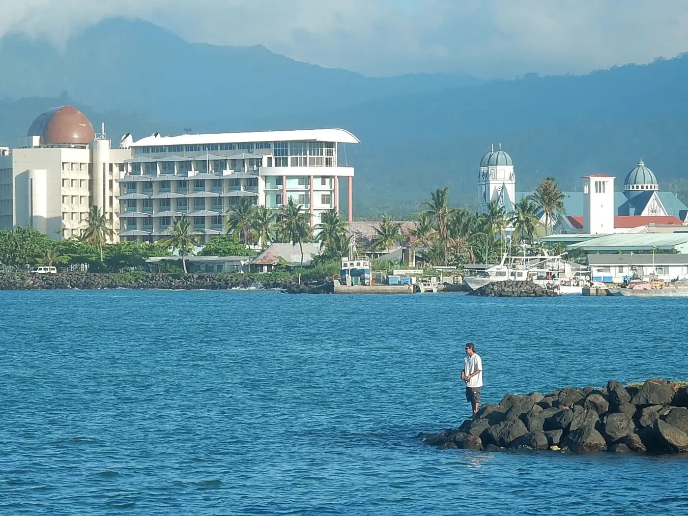 Apia harbour and waterfront, with the white towers of the cathedral and green hills behind