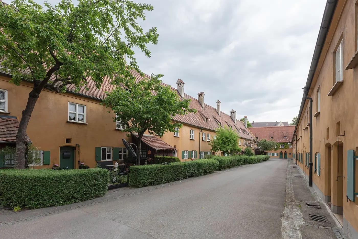 A lane of ochre terraced houses and trees in the Fuggerei, the Augsburg housing estate founded in 1516