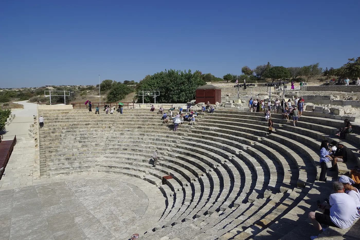 The restored Graeco-Roman theatre at Kourion, its curved stone tiers on a clifftop under a blue sky