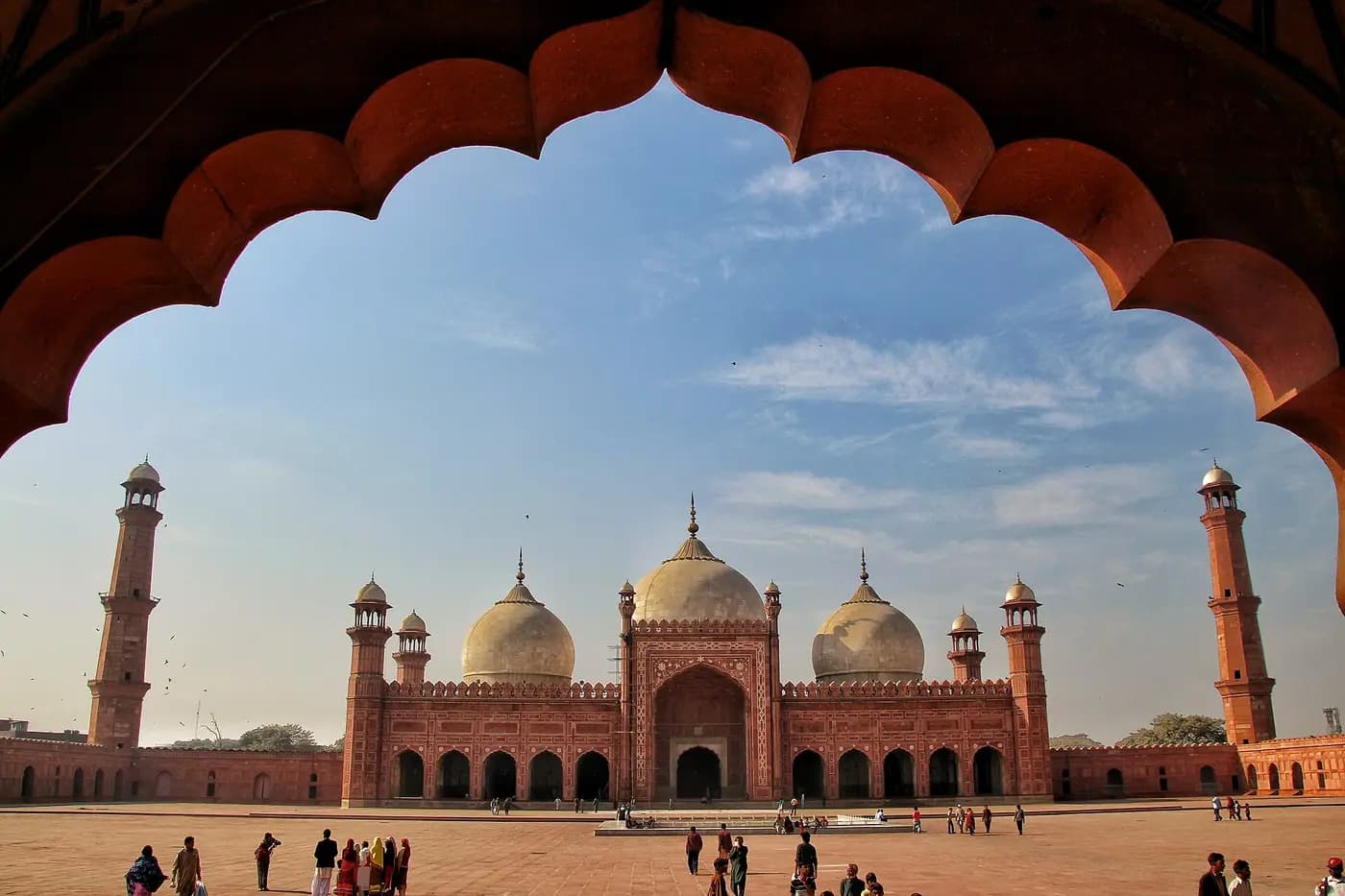 The red sandstone Badshahi Mosque in Lahore, framed by a scalloped Mughal archway