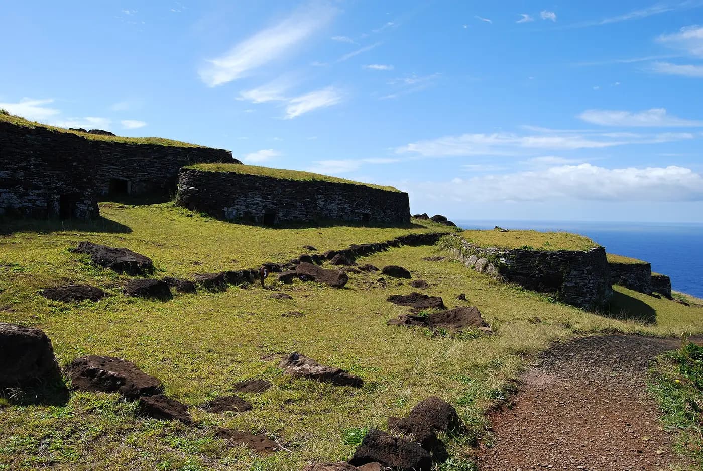 Low stone houses of the Orongo ceremonial village on the grassy rim of Rano Kau, above the Pacific