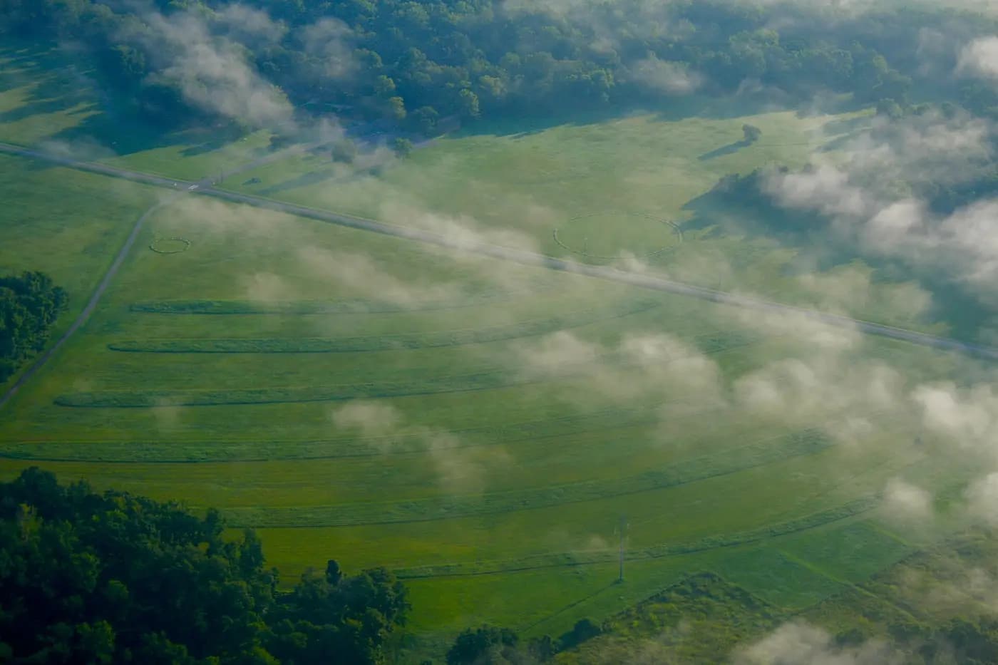 Aerial view of the concentric earthen ridges at Poverty Point, Louisiana, under drifting morning mist