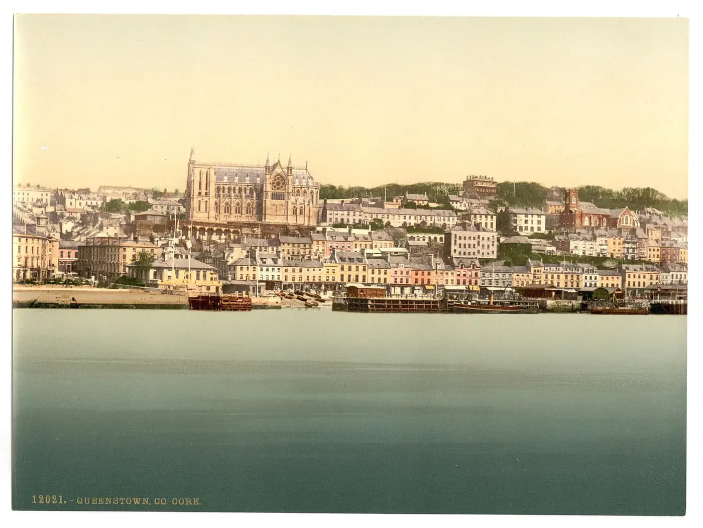 Queenstown's terraced waterfront below its hilltop cathedral, in a colour photochrom of about 1890 to 1900