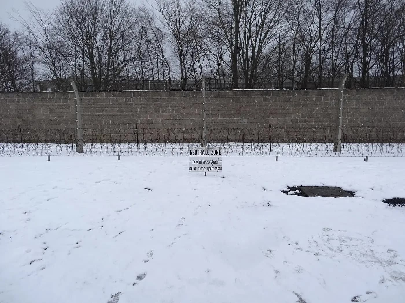 Snow on the 'neutral zone' strip, barbed-wire fence and perimeter wall at the Sachsenhausen memorial