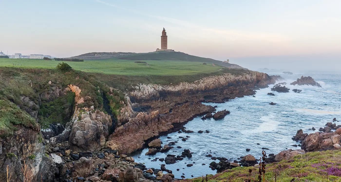 The Tower of Hercules lighthouse on its grassy headland above a rocky Atlantic shore at A Coruña