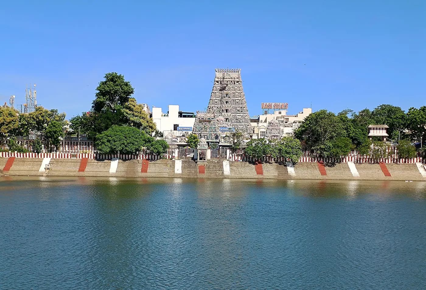 The painted gopuram of Kapaleeshwarar Temple rising beyond the stepped temple tank in Mylapore, Chennai