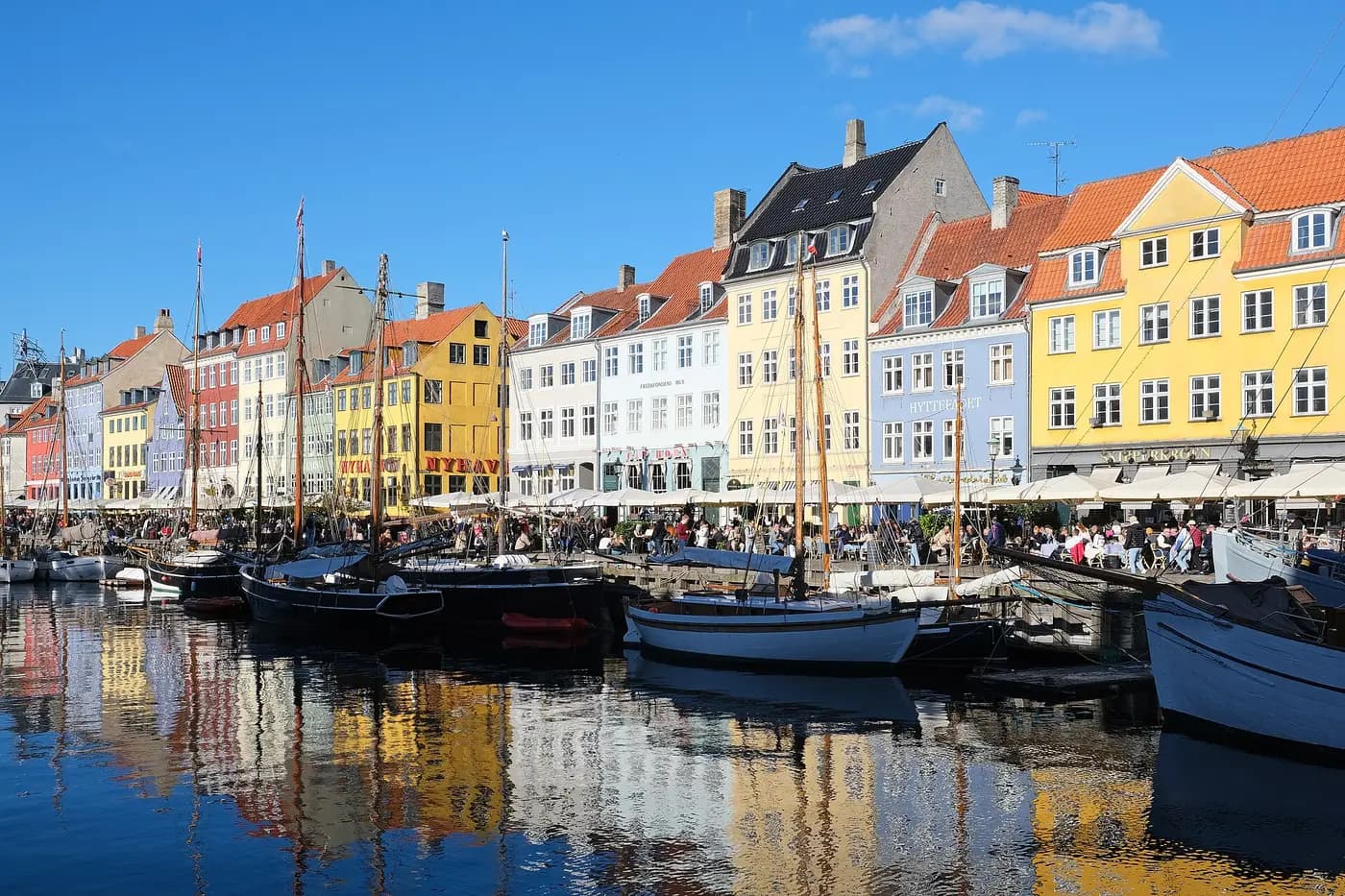 Brightly painted old townhouses and wooden sailing ships reflected in the Nyhavn canal, Copenhagen