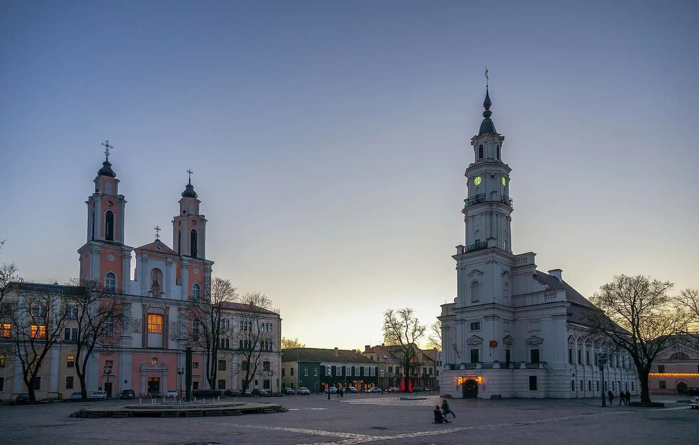 Kaunas Town Hall's white tower and the twin-towered Church of St Francis Xavier on Town Hall Square at dusk