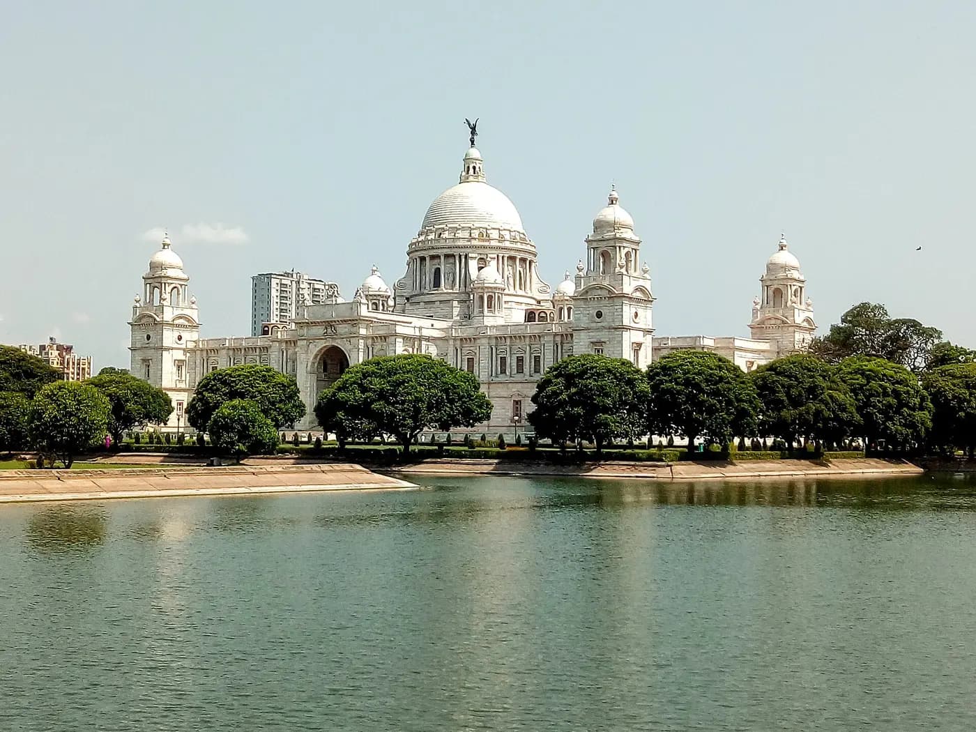 The white marble domes of the Victoria Memorial in Kolkata, reflected in the lake before it