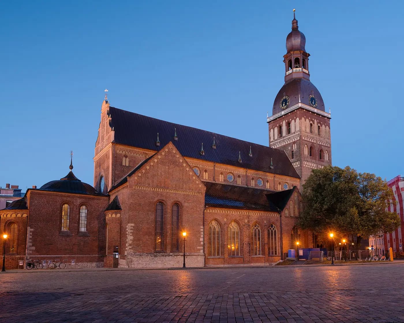 Riga Cathedral's brick nave and tall tower lit at dusk above Dome Square