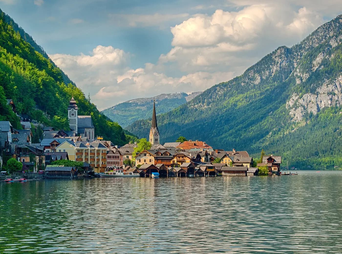Hallstatt's lakeside houses and church spire beneath steep mountains, seen from the lake